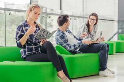 Effiziente Reinigungsprozesse – Team am Arbeitsplatz Drei junge Menschen sitzen auf grünen Sitzbänken und besprechen Unterlagen – effiziente Reinigungsprozesse und Einweisungen